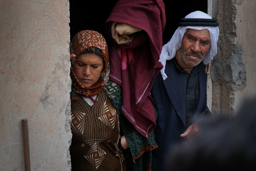 A group of Kurdish refugees look on from their doorway