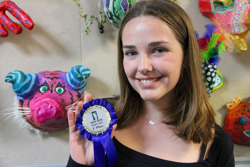 A girl holds a winning rosette.