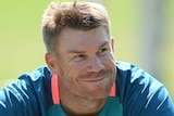 David Warner smiles while sitting down at an Australian team training session
