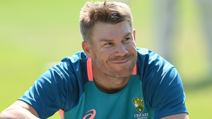 David Warner smiles while sitting down at an Australian team training session