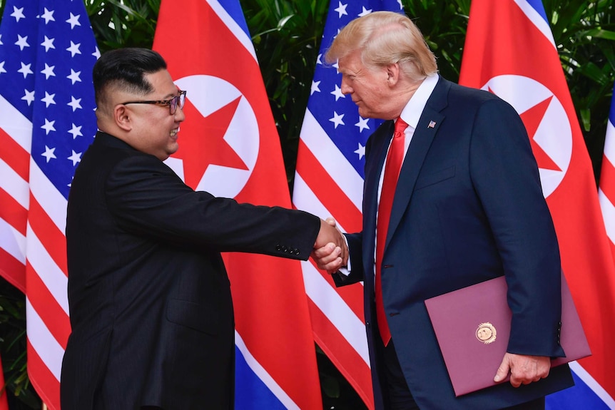 North Korea leader Kim Jong-un and US President Donald Trump shake hands and smile.