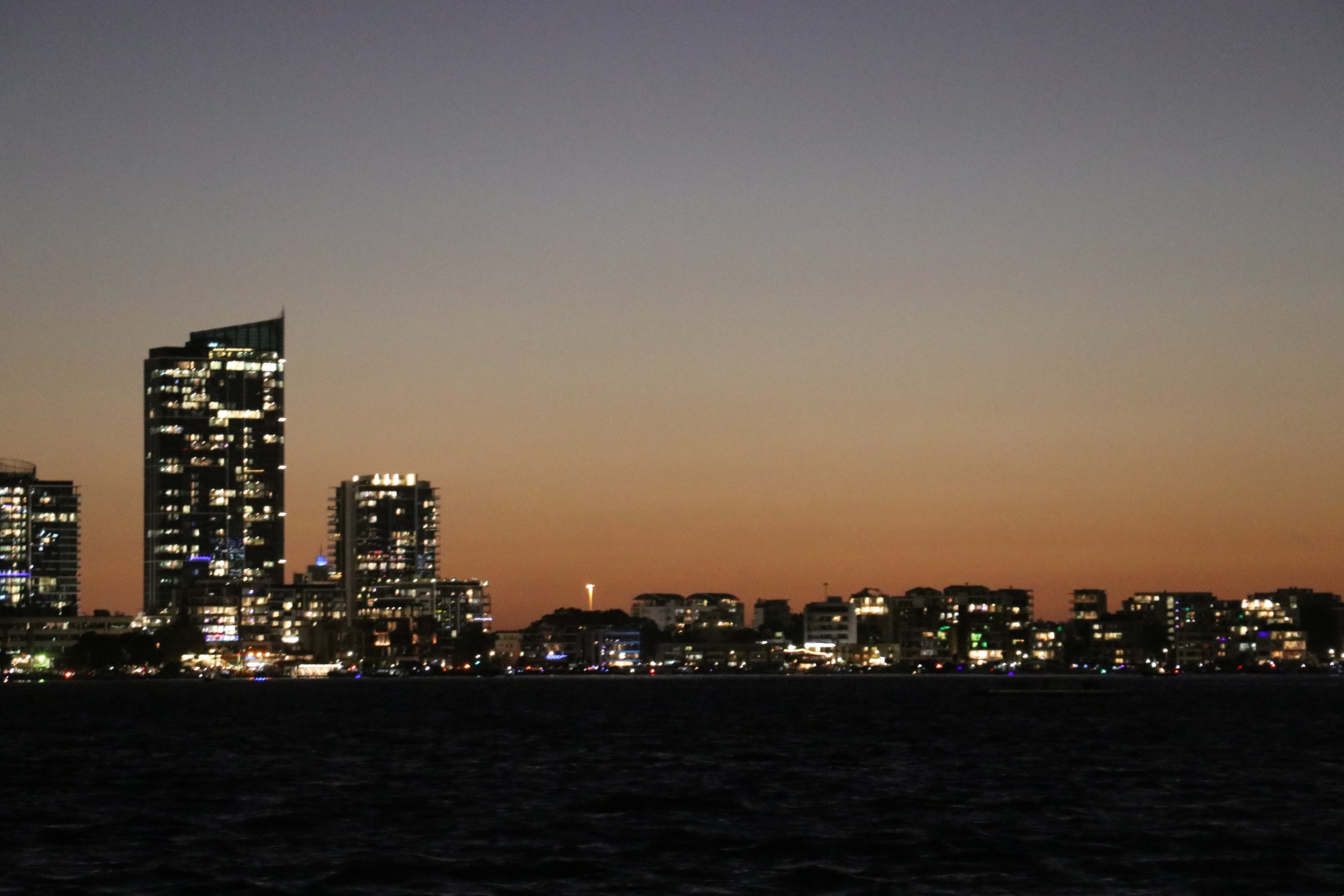 Lights going on in buildings after the sun has set.