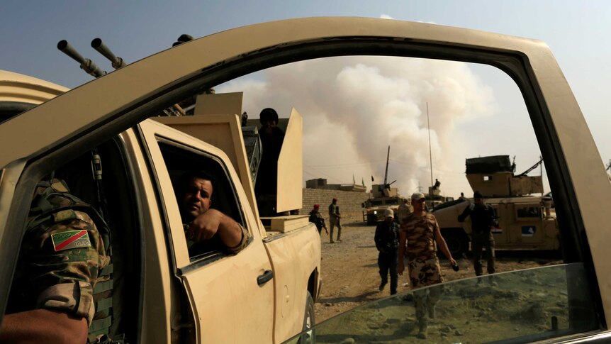 Iraqi army soldiers are seen beside their armoured vehicles.