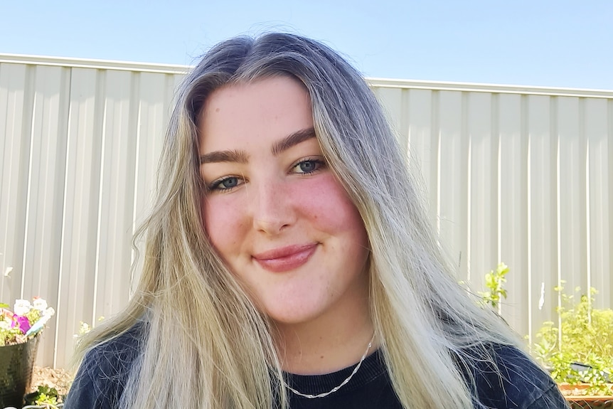 Profile photo of a young woman with a fence backdrop.