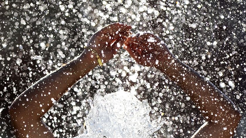 A man splashes water in a fountain on a hot summer's day