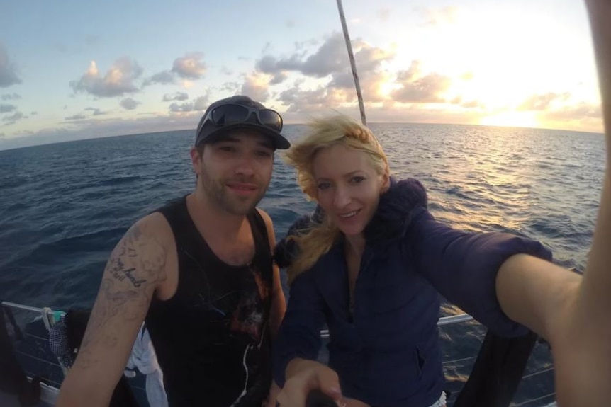 A man and woman smiles for a photo on a boat in the ocean