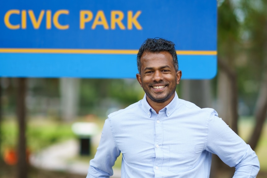 A man, smiling, standing next to a railing.