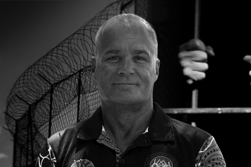 black and white picture of man with barbed fence and prison cell behind