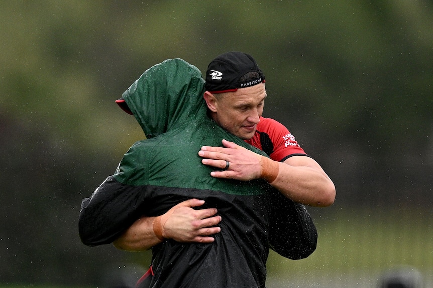 El entrenador en jefe de Rabbitohs, Jason Demetriou (izquierda), es abrazado por el jugador Jack Wighton durante una sesión de entrenamiento.