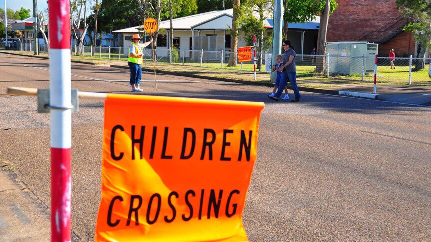 Parent and child walk across the road at a designated school crossing.