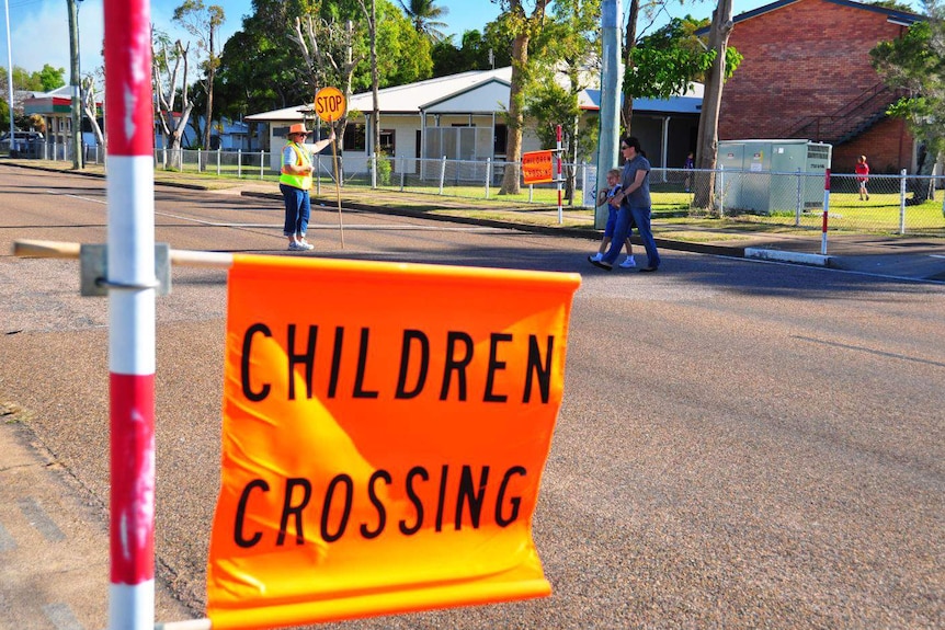 Parent and child walk across the road at a designated school crossing.