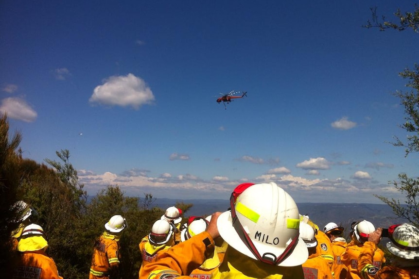 RFS crew watch on as a helicopter water bombs a bushfire at Katoomba