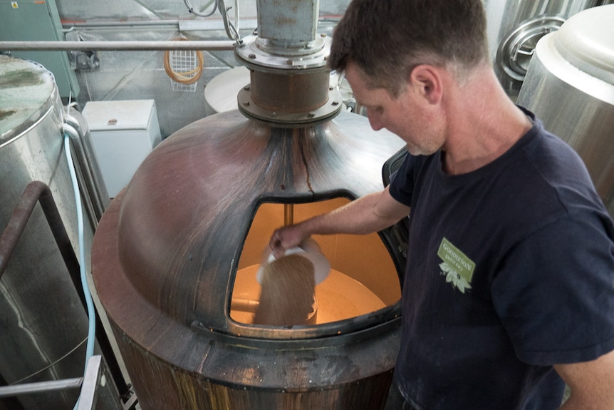 Jeff Goodieson dropping mash into a wheat beer mix.