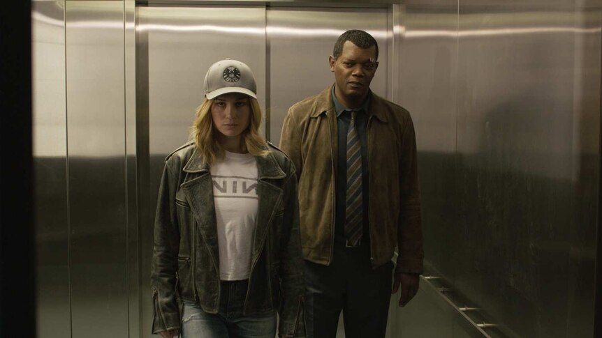 The actors stand side by side in an open elevator, Larson in a baseball cap and a leather jacket, Jackson in a shirt and tie.