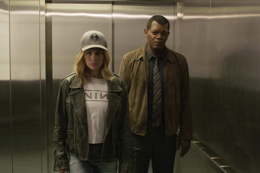 The actors stand side by side in an open elevator, Larson in a baseball cap and a leather jacket, Jackson in a shirt and tie.