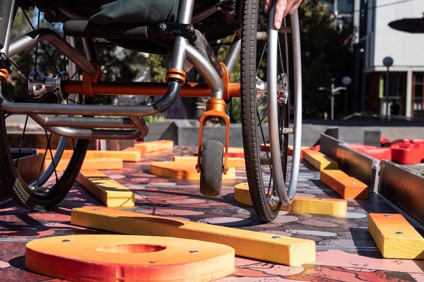 A person lifts the front wheels of a wheelchair to navigate over obstacles