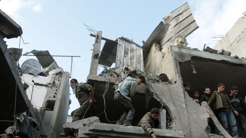 Palestinians survey scene of Israeli air strike on the home of senior Hamas leader Nizar Rayyan