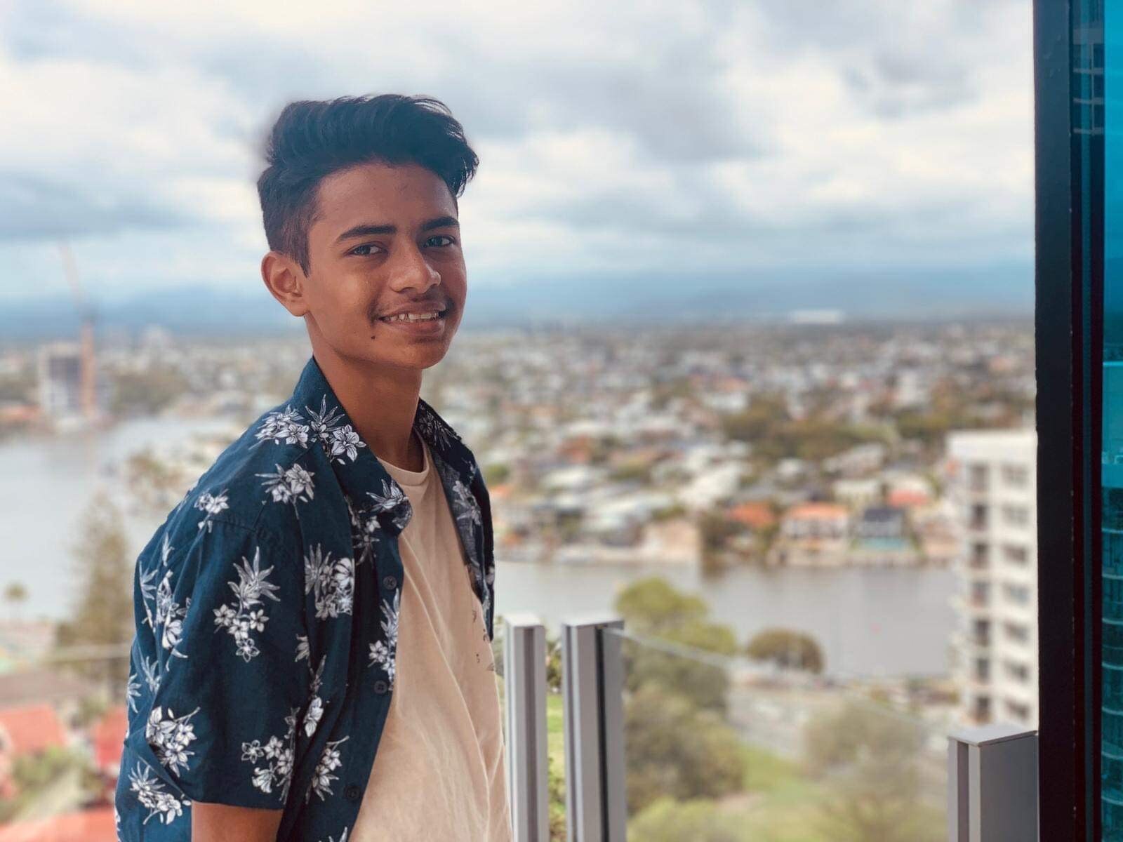 Mohammed Alam looks at the camera with houses and water behind him.