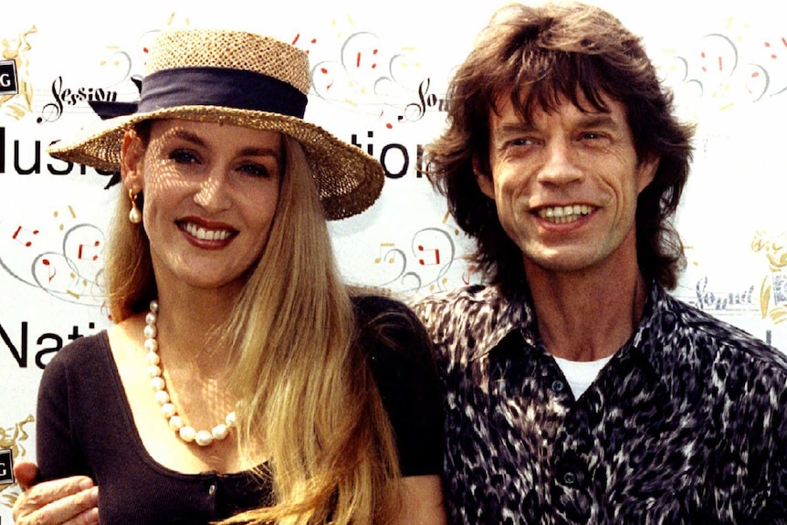 Jerry Hall in a straw hat next to Mick Jagger