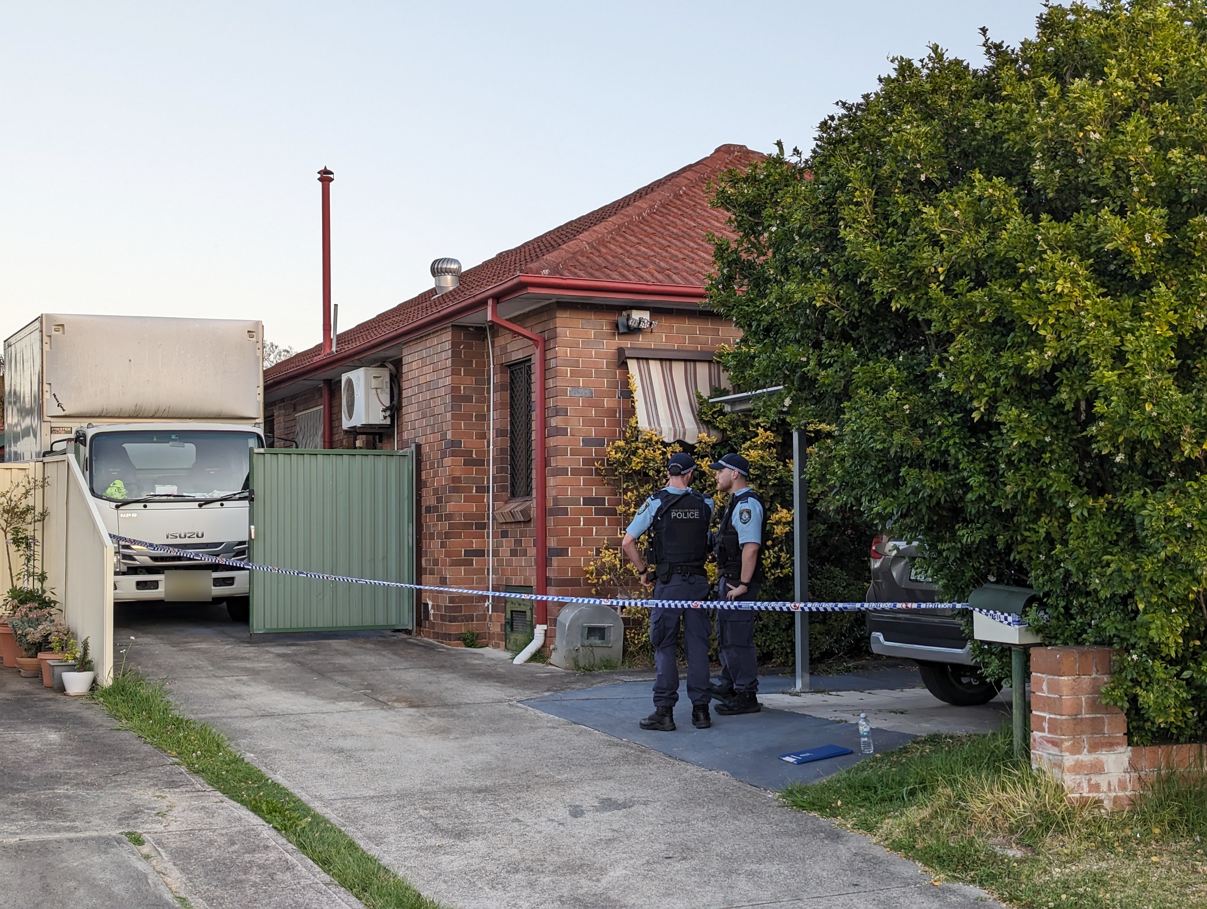 new south wales police officers outside a house in riverwood where the body if a man was found in a truck and a woman in house