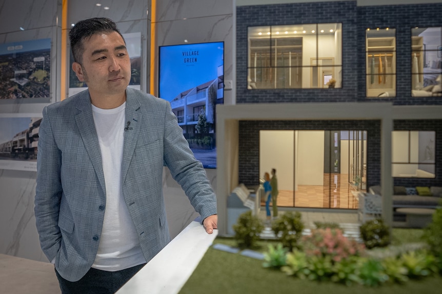 A man of Asian heritage looks at a mock up of a newly built home.