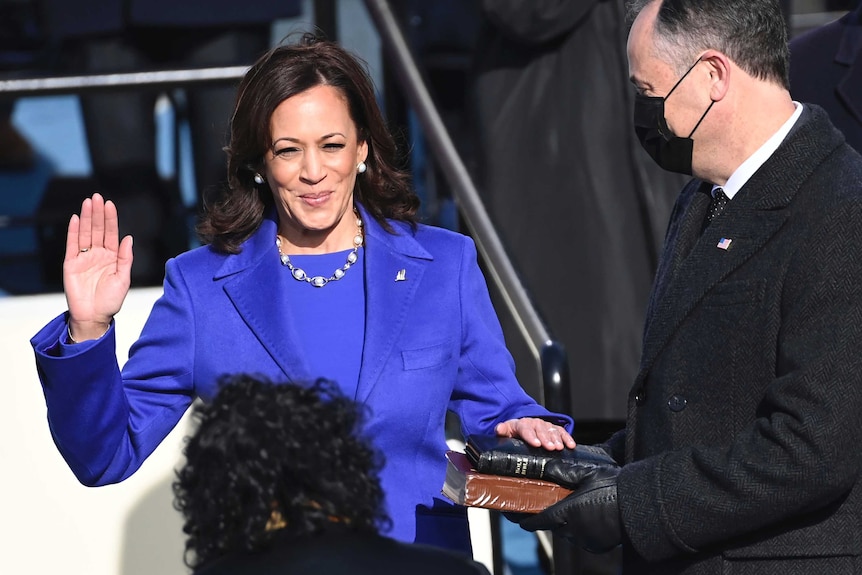 Kamala Harris raises right hand, while left hand is on the holy bible.