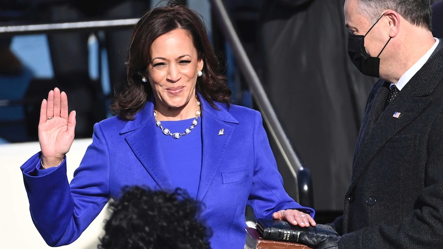 Kamala Harris raises right hand, while left hand is on the holy bible.