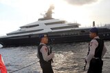 Police officers stand guard as luxury yacht Equanimity is seen in the background off Bali.