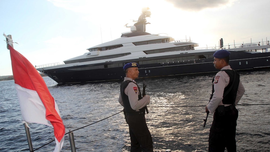 Police officers stand guard as luxury yacht Equanimity is seen in the background off Bali.