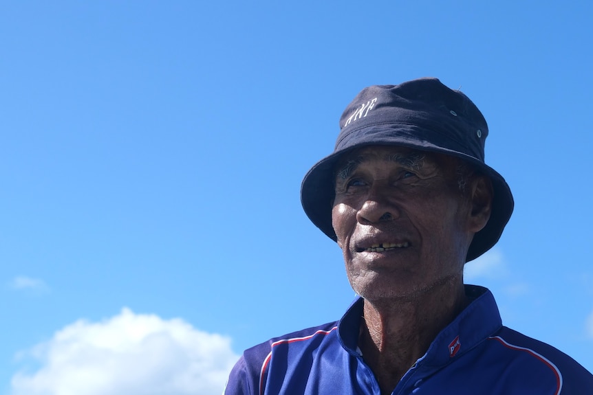 A Cocos Malay man in a bucket hat looks at the sky. 
