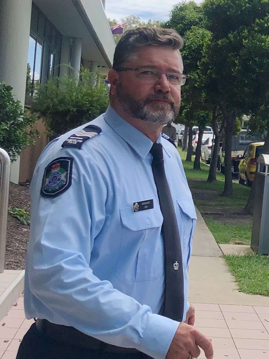 A police officer in uniform walking from a court house.