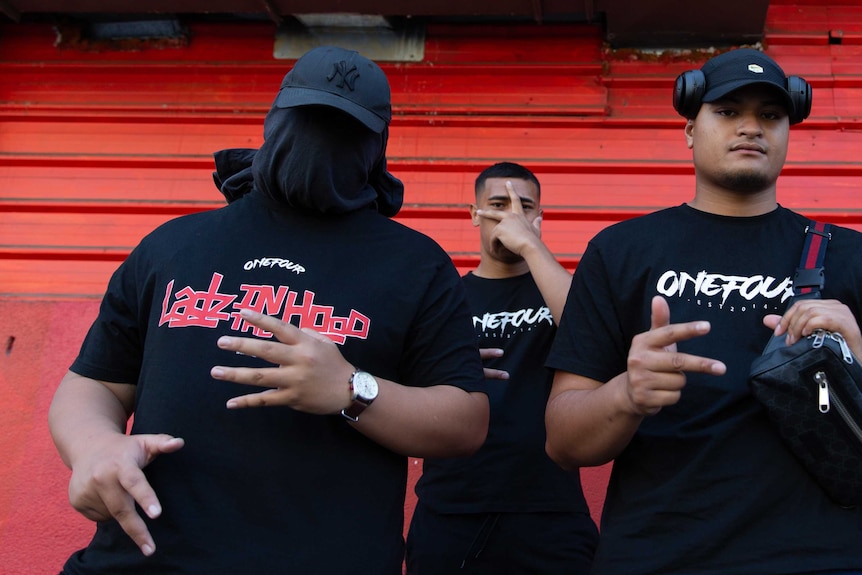 A man sitting has a t-shirt wrapped around his head to conceal his identity.