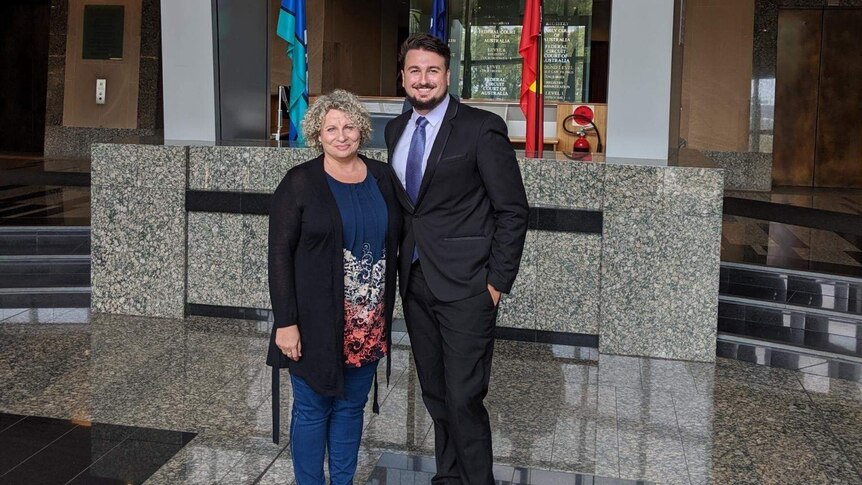 Woman with curly blond hair and man wearing a suit standing in the foyer of the Federal Court in Brisbane.