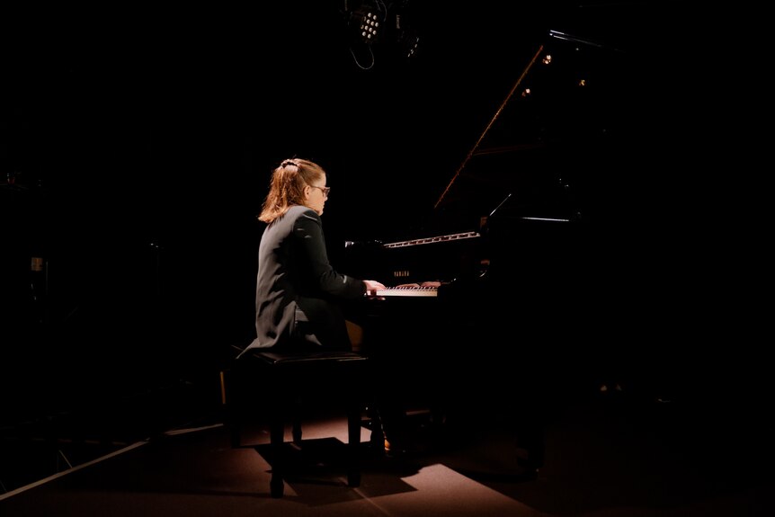 A woman on a piano in a dark room