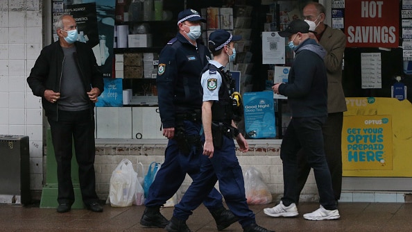 Police officers in masks walk across a crowded shop front