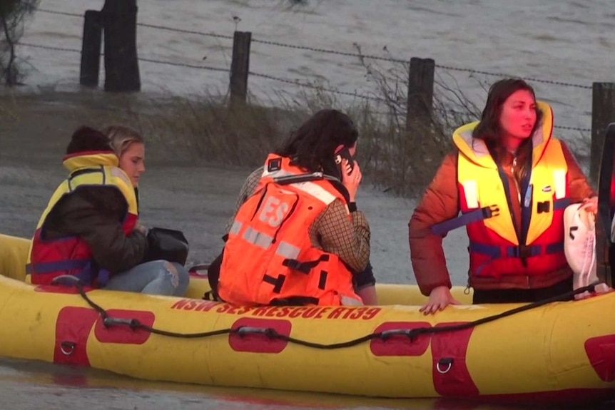 Three women wearing lifejackets sit in an inflatable SES dinghy.