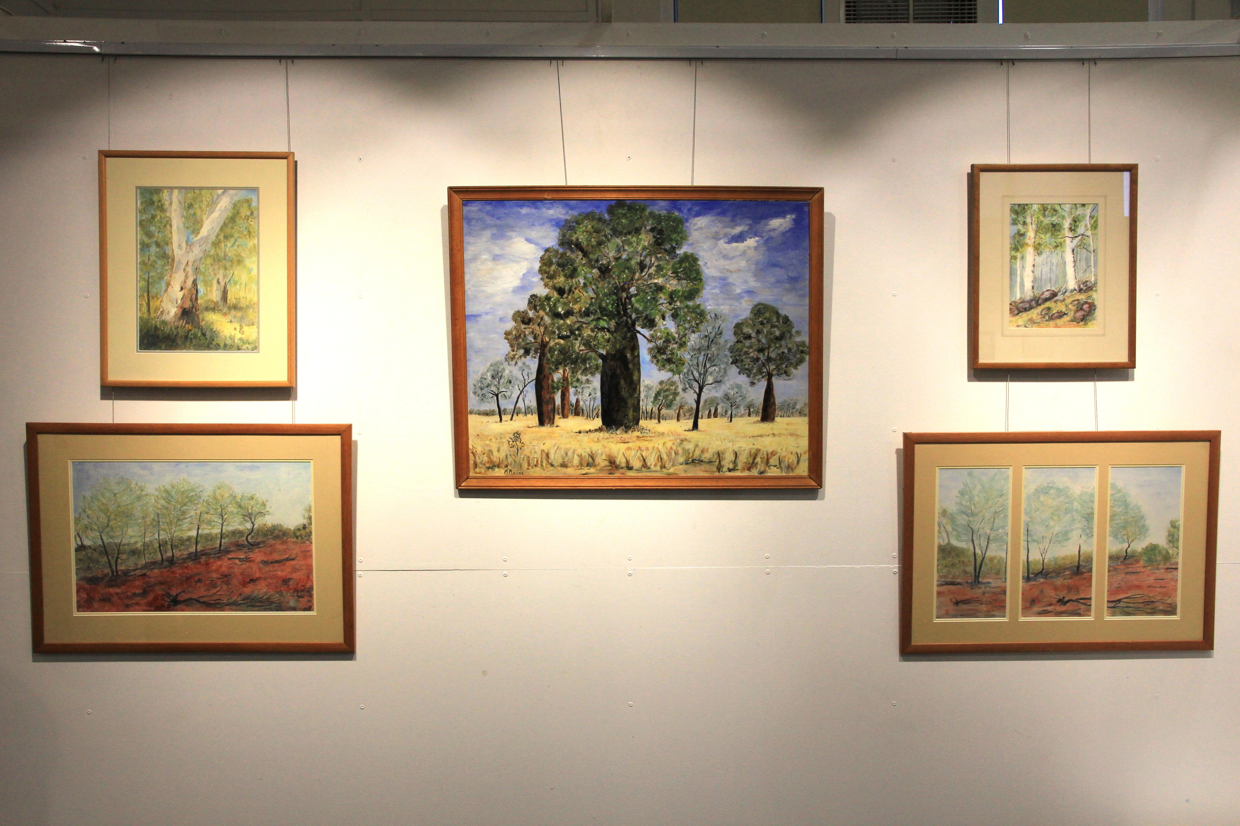 Cinco pinturas de cenas do mato estão penduradas na parede.