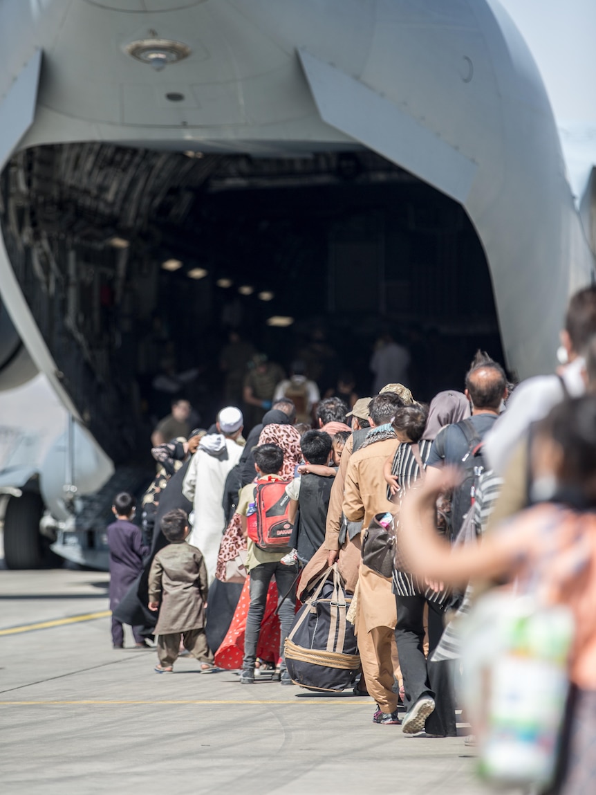 A line of Afghan refugees preparing to board a military plane.