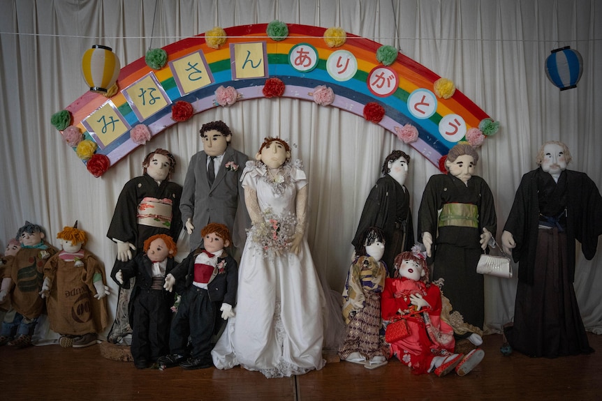 A group of dolls dressed in wedding attire are lined up for a ceremony.