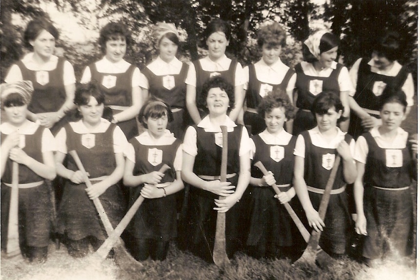 Black and white photo of young girls holding camogie sticks