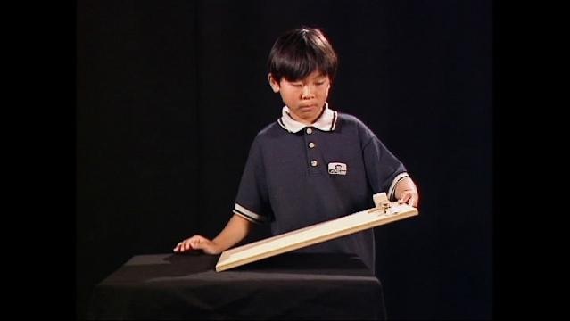 Boy holds up wooden plank to approximate a ramp
