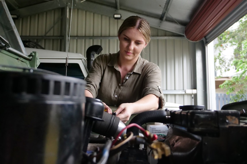 An image across an exposed engine of a young woman working on the engine. 