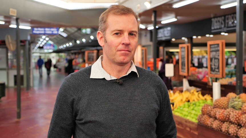A man stands in the middle of a fresh food market.