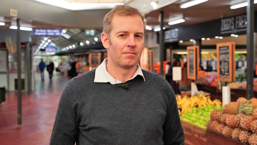 A man stands in the middle of a fresh food market.