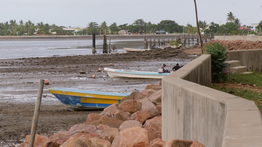 Low tide on remote Torres Strait island, mudflats and small fishing boats, village behind 