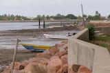 Low tide on remote Torres Strait island, mudflats and small fishing boats, village behind 