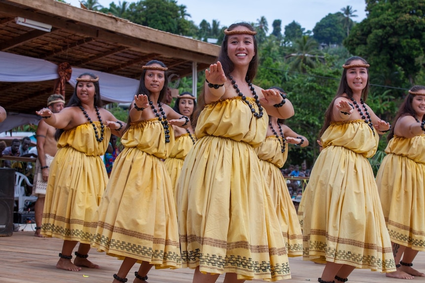 Women in yellow Hawaiian cultural attire dance hula 