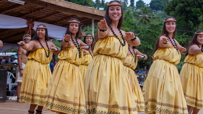 Women in yellow Hawaiian cultural attire dance hula 