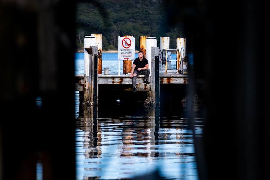 Dean sits on the wharf in Manly.