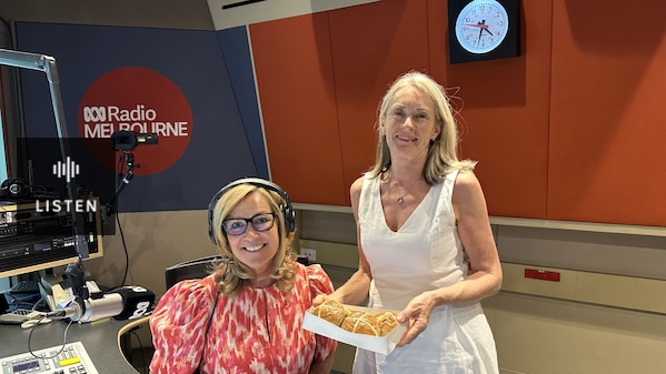 Two women smiing in radio studio holding hot cross buns . Has Audio.